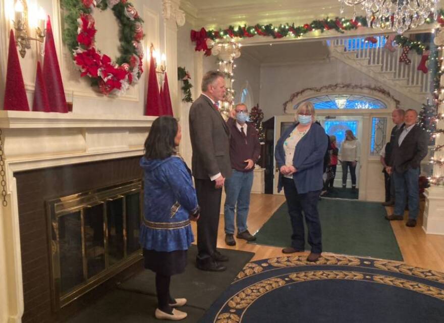 People stand in a large foyer decorated for the holidays.
