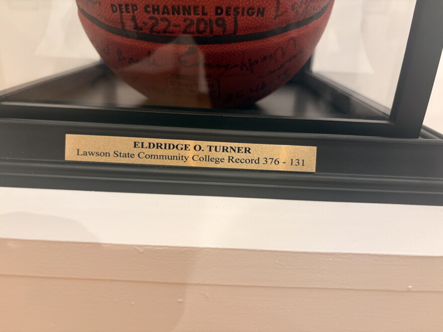 Close-up of a plaque identifying Eldridge O. Turner and displaying the inscription “Lawson State Community College Record 376-131,” alongside a signed basketball.