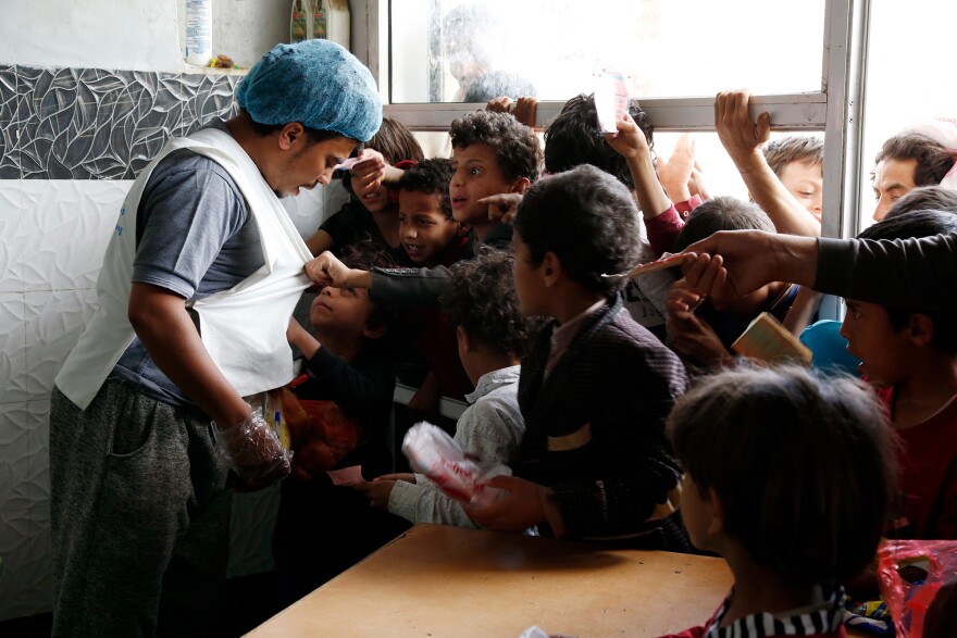 Yemeni children from families who are affected by the war talk to a worker to receive their lunch meals at a charitable center in April. Tens of thousands of the country's people are starving to death and another 5 million are on the brink.