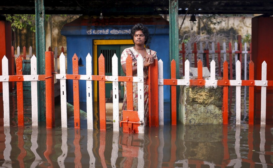 A woman stands outside a submerged temple on Friday.