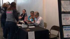 Election judges and a visitor to a table at Eastland Mall for early voting.