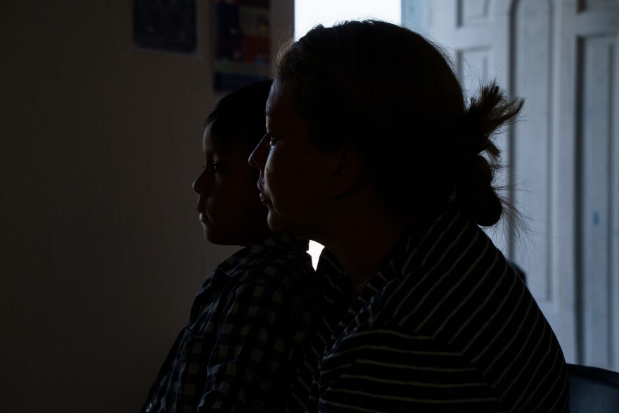 Levis and her son sitting in shadow with an open door in the background.