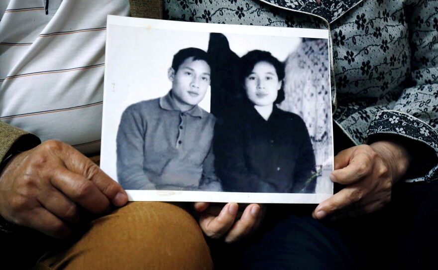 Canh and Ri hold a photo from their early days of courtship in 1971, when he was in North Korea on an internship.