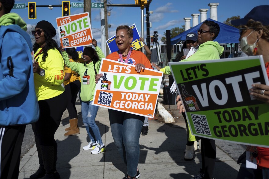 FILE - People gather during a get out the vote rally Nov. 27, 2022, in Atlanta, during early voting for the Senate runoff election. Voters in Georgia appear to have navigated the strict election law passed last year by Republicans with little difficulty. But voting rights groups say it’s too soon to assess the full impact of the law, since it’s not certain how many voters may have been dissuaded from casting a ballot. (AP Photo/Ben Gray, File)