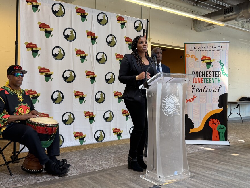 Nikia Washington, coordinator of the Rochester Juneteenth Festival, delivers closing remarks during a ceremony announcing this year's event. Behind her to the right is Simeon Banister, president and CEO of the Rochester Area Community Foundation and leader of The Greater Rochester Martin Luther King Jr. Commission, and drummer Shenuti Nehast Kawaida.