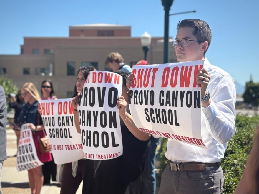 Demonstrators at a news conference make a show of support for parents suing the Provo Canyon School on June 15, 2026.