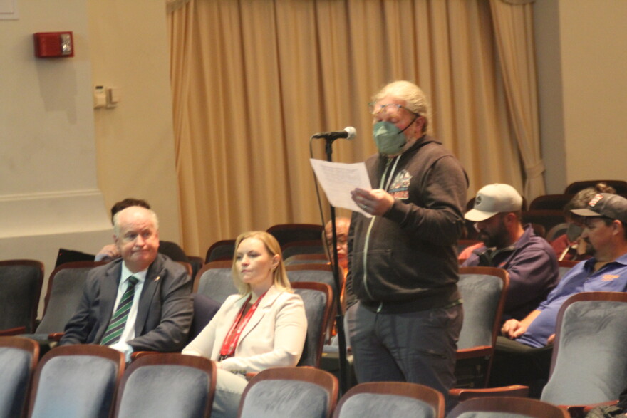  A commentator speaks into a public microphone before city officials. 