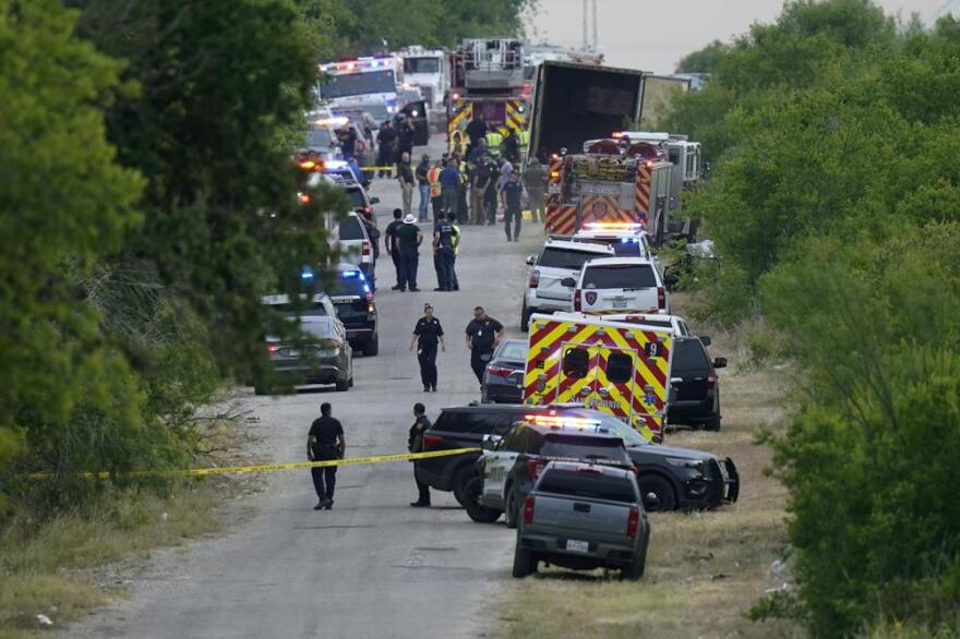 Police work the scene where dozens of people were found dead in a semitrailer in a remote area in southwestern San Antonio on Monday.