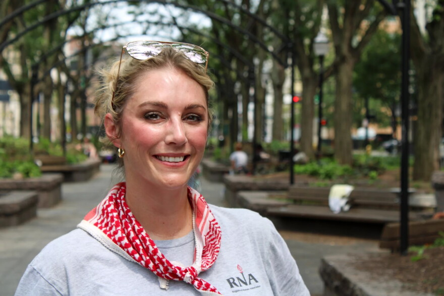 a blonde woman in a park smiles at the camera 