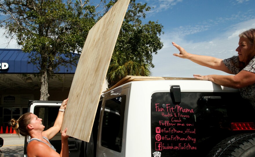 Megan Daniel (left) gets a hand from a stranger, Delene Cole, as she loads plywood she intends to use as storm shutters ahead of Irma on Tuesday in St. Petersburg, Fla.