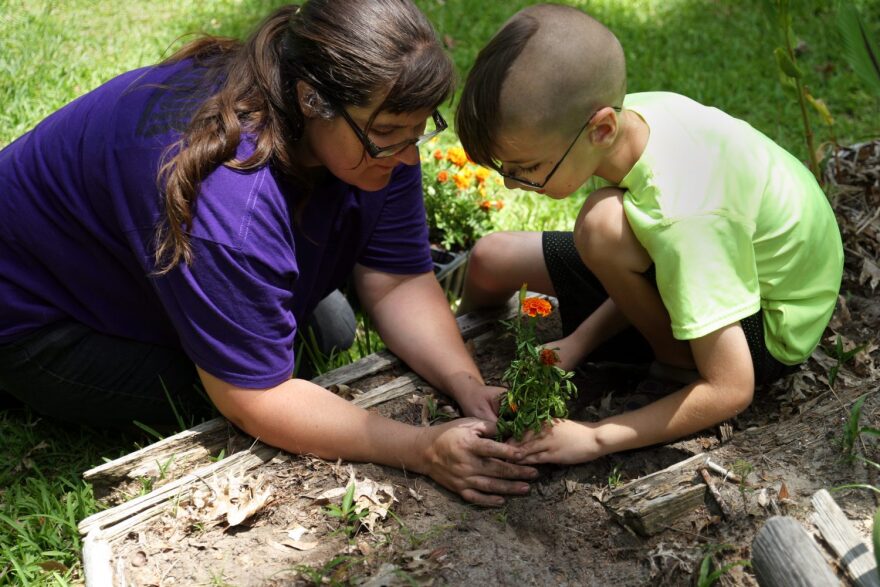 Kelly Johnson and her 8-year-old son, Aiden, plant marigolds. The entire family is part of the therapy at 10 CAN because the founder, Matthew Burke, believes that if you help the family of the veteran, you end up helping the veteran too.