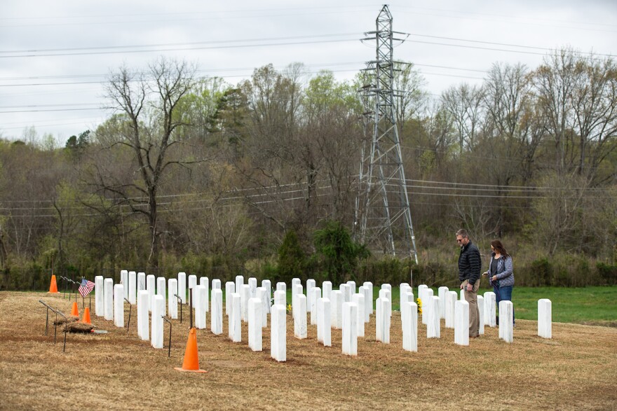 Ivar Lonon, left, and his wife Paige Lonon, right, look at the small plot where the remains of Ivar's father and mother were buried at Salisbury National Cemetery in Salisbury, N.C., on Thursday, March 26, 2020.