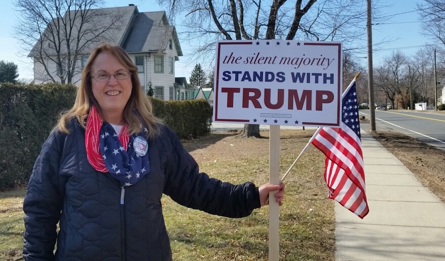 woman holds Donald Trump sign and small American flag