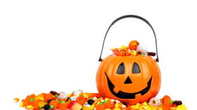 Halloween Jack o Lantern bucket overflowing with candy, side view isolated on a white background