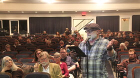 A man speaks into a microphone at a public hearing. 