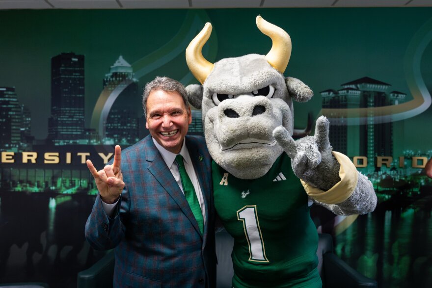 Moez Limayem stands next to Bull mascot. 