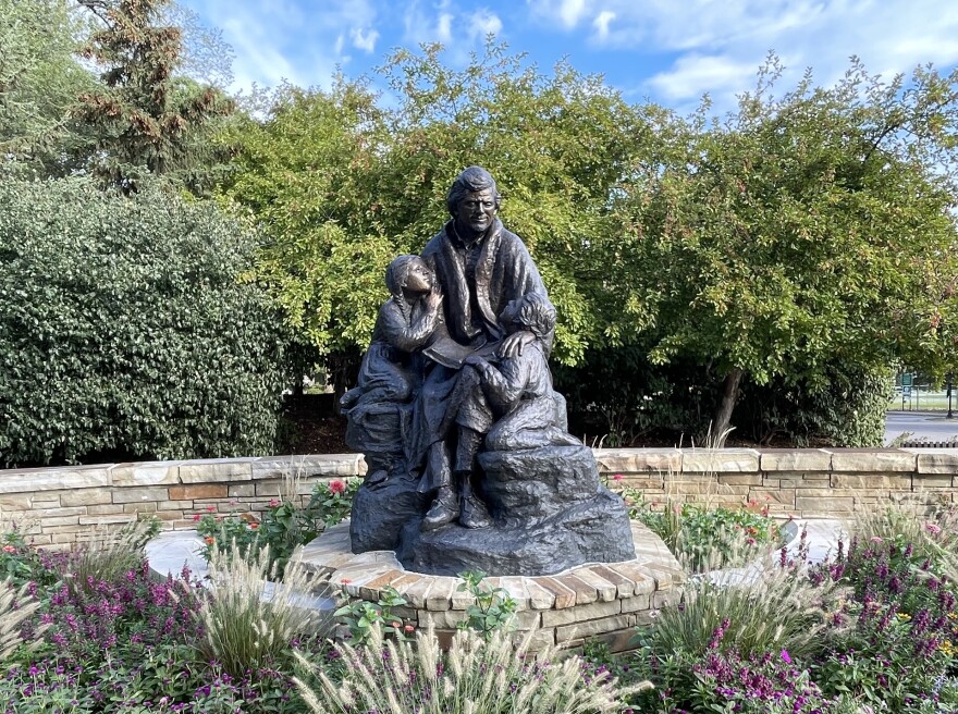Bronze, life statue of a sitting Chief Charles Bluejacket with two children leaning on his knees.