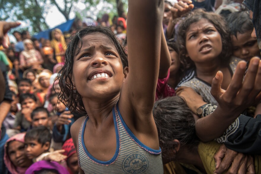 Girls reach out for food handed out by a volunteer organization in the Kutupalong refugee camp in Bangladesh.