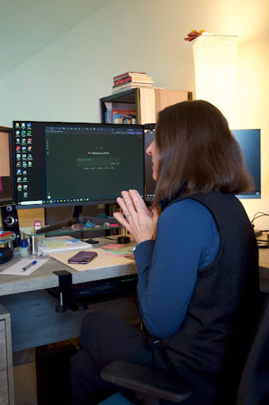 A woman sits at a computer. 
