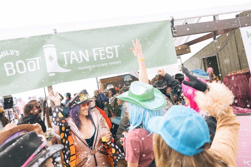 Women in colorful wigs and ski outfits dance at the base of Sunlight Mountain Resort during Boot Tan Fest on March 29, 2024. The all-women’s ski and snowboard festival was started by Carbondale resident Jenny Verrochi.