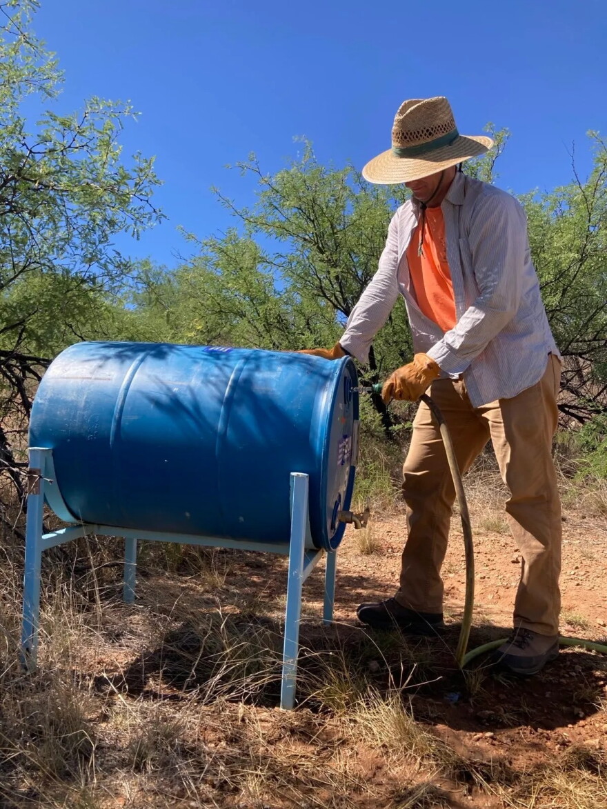 A volunteer for Humane Borders refills a water barrel in the desert. (Photo courtesy of Humane Borders)