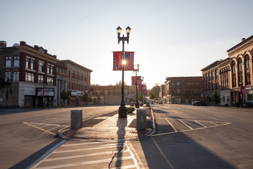The sunrise shines through some streetlight flags in an empty town square in Houlton, Maine.