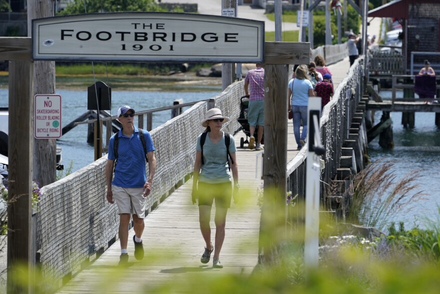 Visitors walk on The Footbridge, Wednesday, July 7, 2021, in Boothbay Harbor, Maine. The state has one of the highest vaccination rates in the country with more than two-thirds of the population over age 12 fully vaccinated.