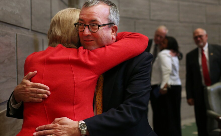 Sen. Joe Keaveny receives a hug while walking out of the senate chamber on Friday. Keaveny announced he will resign from the senate to become an administrative law judge.