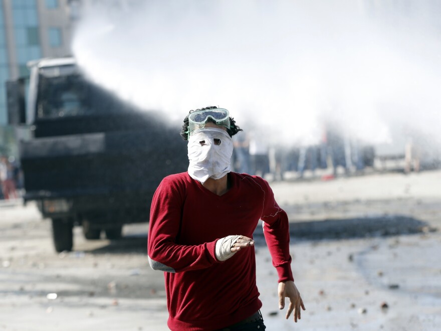 A protester runs as a crowd control vehicle fires a water cannon in Istanbul's Taksim Square on Tuesday.