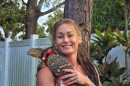 Woman with tattoos holds lizard on chest