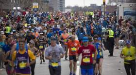 Runners pour over the Mass Pike Bridge at the Mile 25 marker welcoming them to Boston. (Jesse Costa/WBUR)