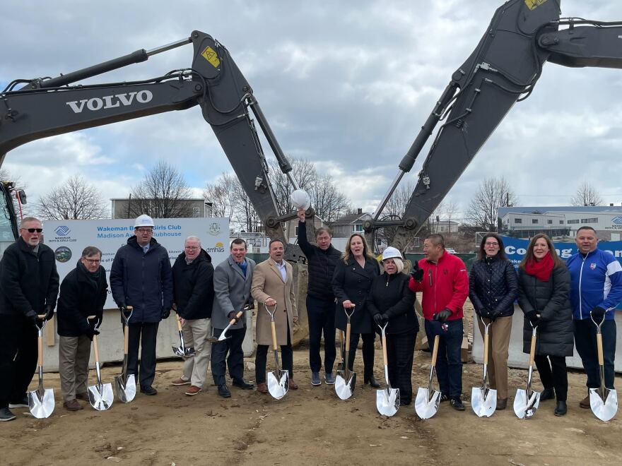 Governor Ned Lamont, hard hat raised, breaks ground on the new Boys and Girls Club location in Bridgeport with other city and state officials.