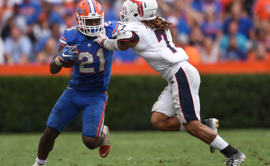 Florida running back Kelvin Taylor (21) stiff arms FAU defensive back Cre'von LeBlanc (7) while trying to break free. (Greenberry Taylor/ WUFT News)