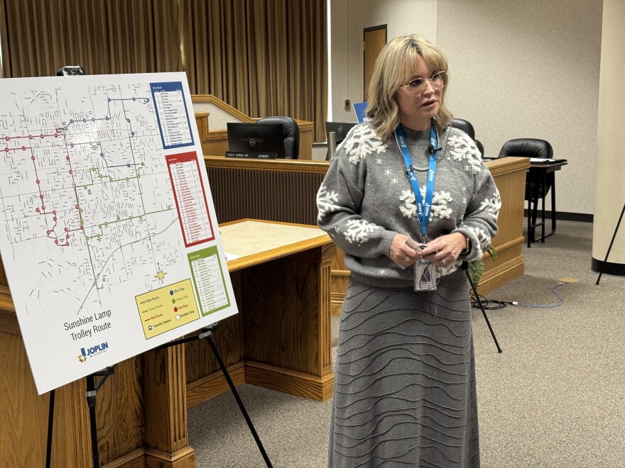 Transportation Coordinator Gina Thompson standing next two the map of the new routes for the Sunshine Trolley. There will be a red, blue and green route, spreading the transportation all over the city.