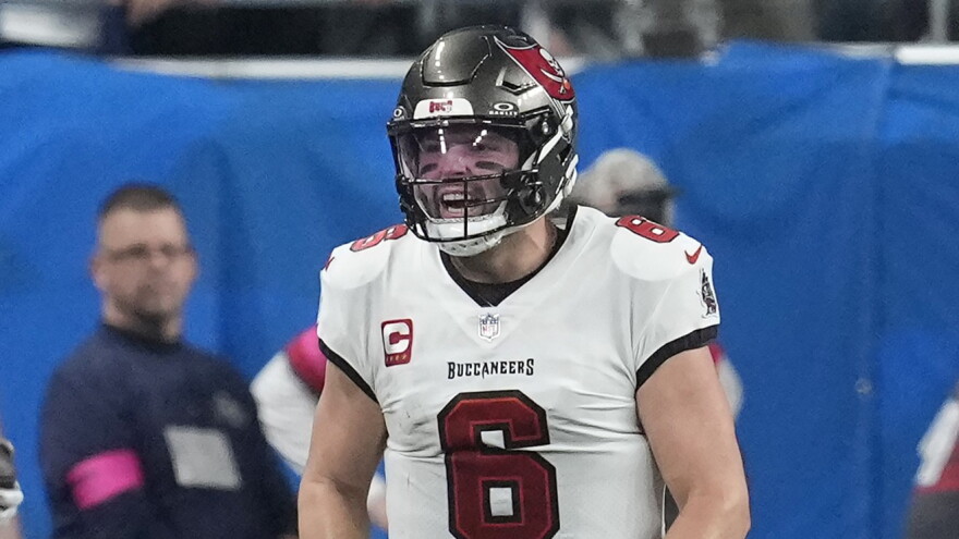 football player with white jerseys and pewter helmet celebrate on the field.
