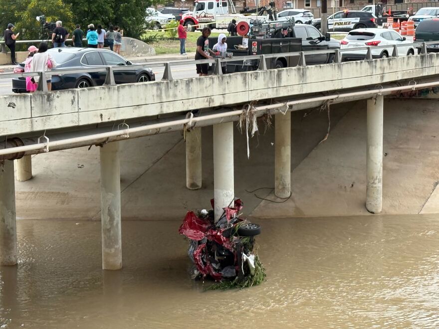 A car pushed into the creek by flood waters and the impact after it was pushed into one of the bridge's support beams.