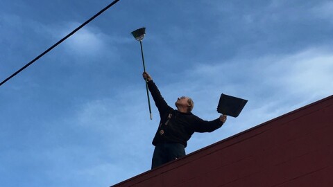 George Brown triumphantly lifts the broom he used to sweep the roof and surrounding area of The Kiva every day.