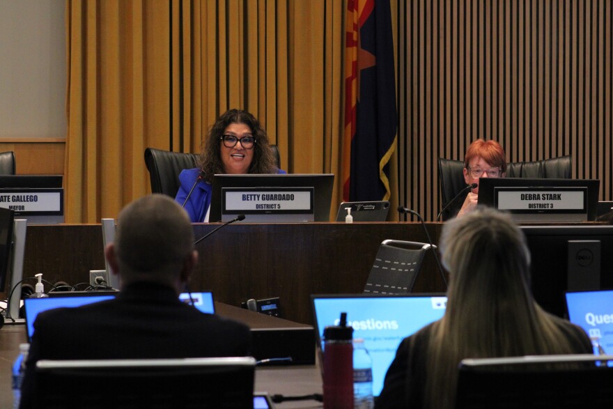 city council member sits behind a desk with two people looking at computers are in the foreground