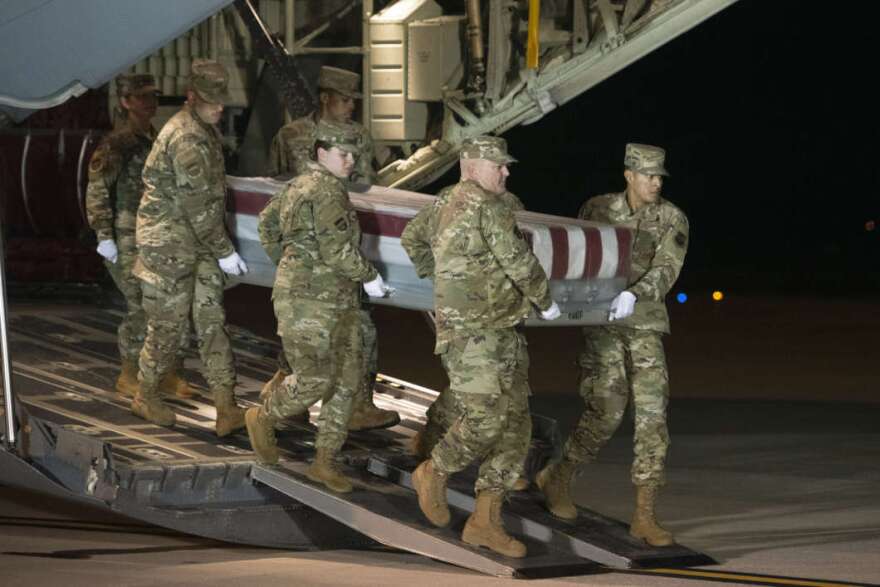 An Air Force team moves a transfer case containing the remains of one of the young sailors killed after a Saudi military student opened fire at a Pensacola naval base last month. Officials are expected to soon announce that about 12 Saudi military students will be expelled from the U.S. CREDIT: Cliff Owen/AP