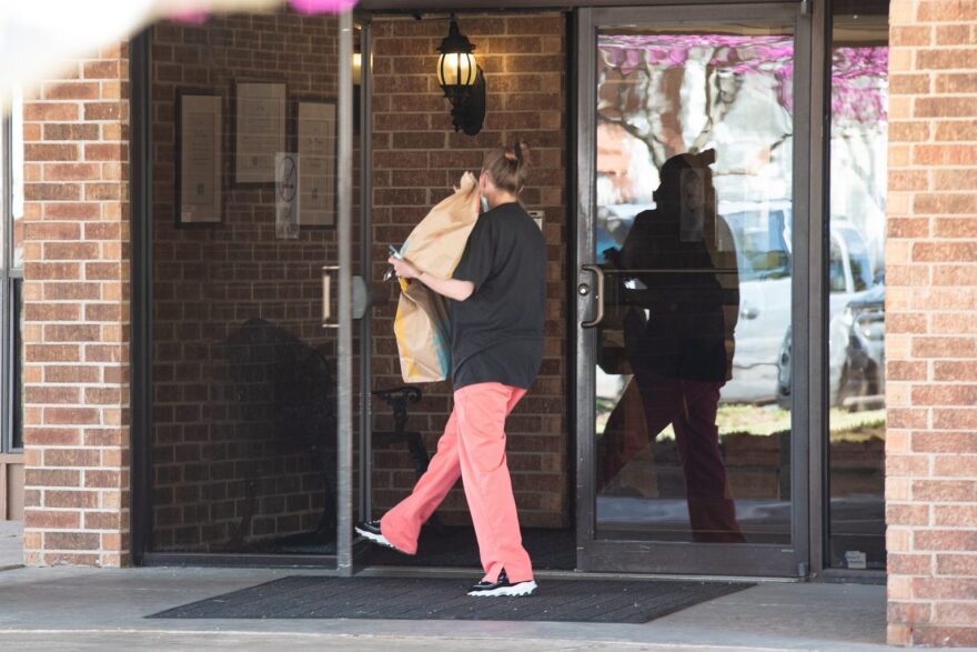 A woman is seen bringing food into the Grace Skilled Nursing and Therapy in Norman on March 26, the day after a state surveyor conducted an on-site investigation.