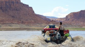 A motor churns up beige-colored river water as a boat veers through a red-rock canyon at Lake Powell in Utah on July 5, 2022. The reservoir's recreation industry has struggled to adapt to record low levels over the past two years.