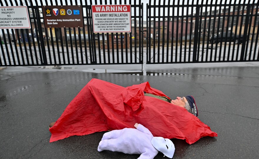 Veterans for Peace Director Mike Ferner lays in front of the gate to the Scranton Army Ammunition Plant.