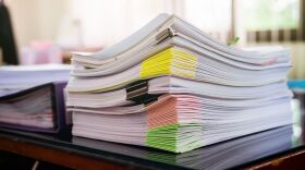 Stack of papers with clips and color coding on a desk.