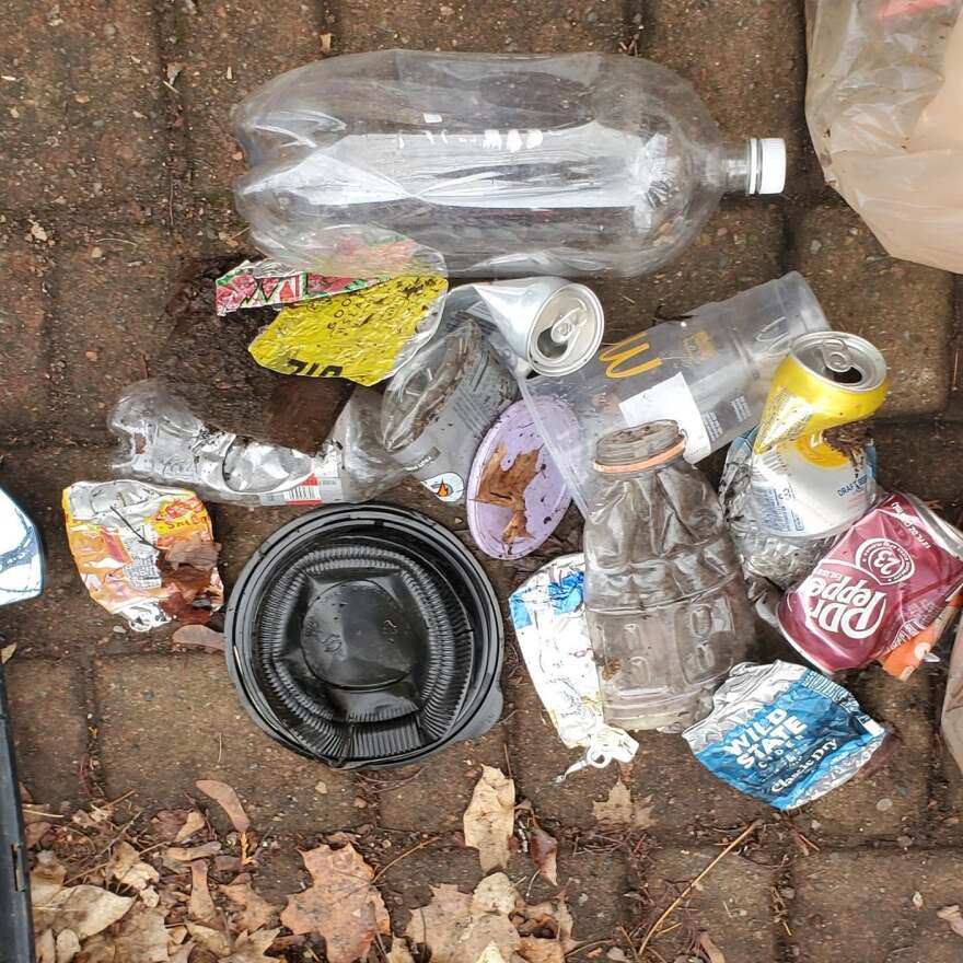 Overhead view of about a dozen pieces of litter on a brick sidewalk