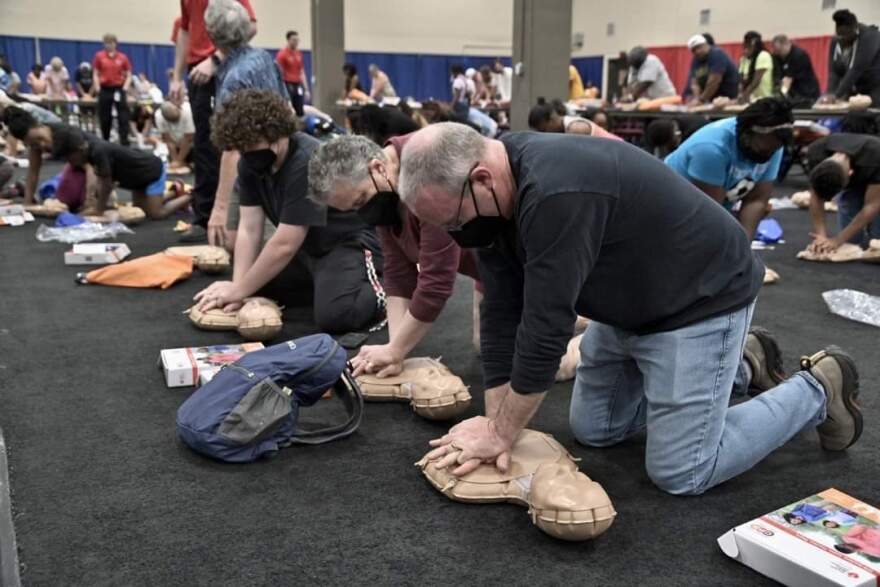 Dozens of people practice CPR on practice dummies.