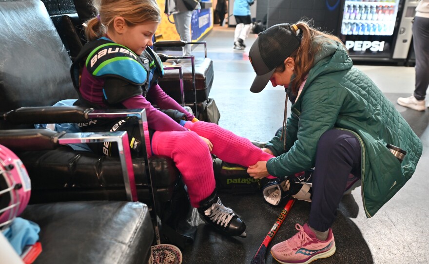 Jeannie Pisaneschi helps her daughter, Calla Pisaneschi put on socks before playing hockey.
