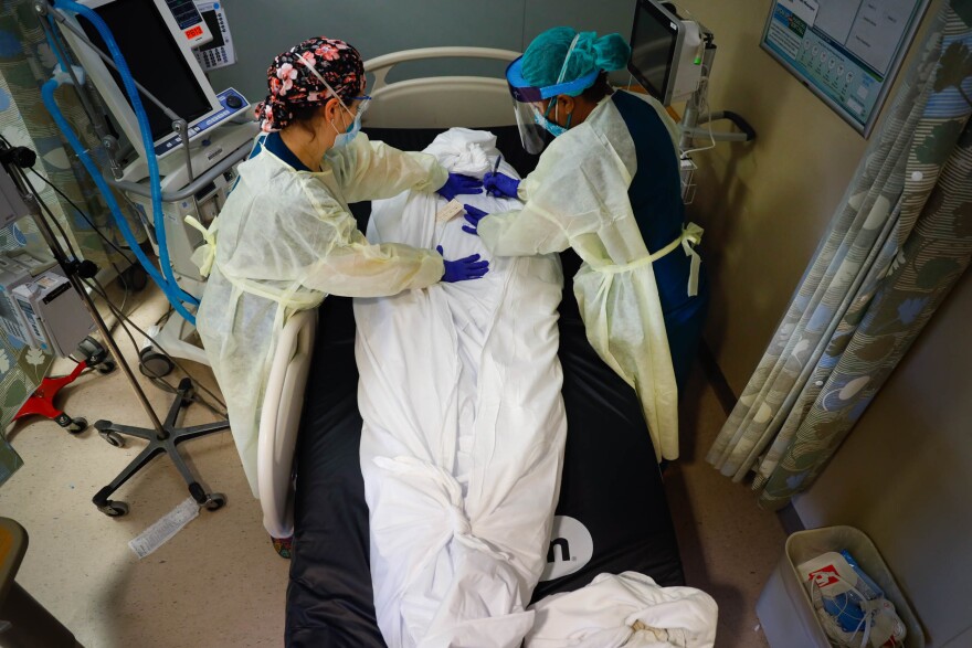Nurse educator Katie Demelis and nurse manager Nydia White wrap the the body of a patient who died of COVID-19 at Mount Sinai South Nassau hospital in Oceanside, N.Y., on April 15, 2020.