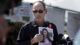 Fred Guttenberg, father of Jaime Guttenberg, who was killed in the Parkland massacre, holds a photo of Jaime as he listens to questions from reporters in front of Marjory Stoneman Douglas High School in March 2018. 