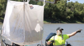 A bag of invasive carp is removed from a boat and given to the commercial fisherman for use as bait.