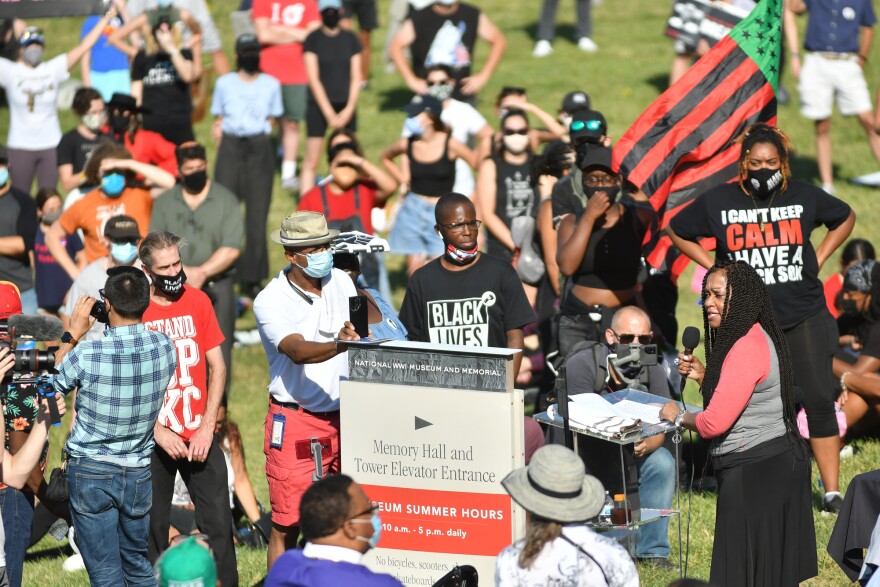 Gwendolyn Grant, president of the Urban League, leads the protestors in a chant of "provoke the vote" after the group settled into the grounds beneath the World War I Museum and Memorial on Friday following their protest march from downtown.